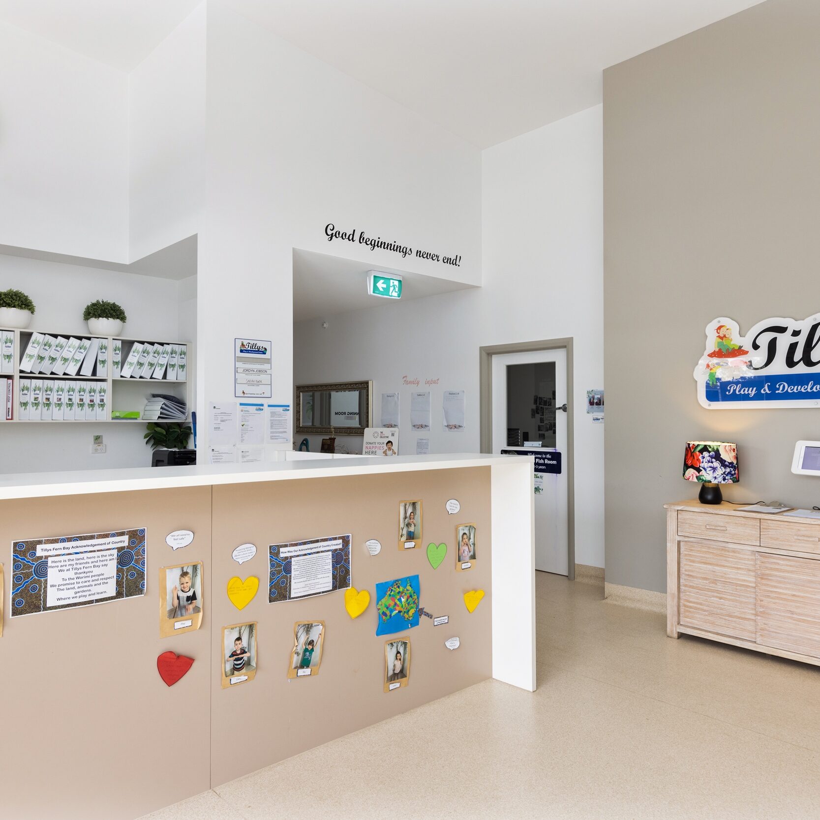 Reception area of Tilly Child care features a welcoming desk with a wall display of children’s crafts, a colorful sign, and organized shelves, conveying a warm, inviting atmosphere.