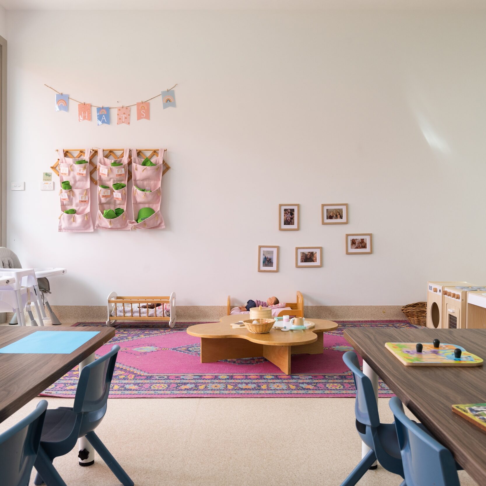 Bright and inviting preschool classroom with small tables and chairs, colorful art supplies, wall decorations, and toys, creating a cheerful learning space.