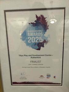 Framed certificate with blue and purple watercolor background, text: "Narragunnawali Awards 2025," "Tillys Play and Development Centre - Rutherford, Finalist, Early Learning Category."