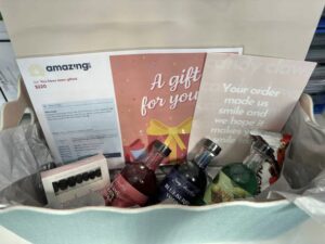 Tillis Gillieston Heights A gift package with colorful drinks and chocolates, accompanied by a gift card and a note of gratitude. The mood is festive and appreciative.