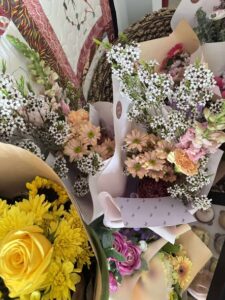 Tillys Waratah 2 A vibrant collection of floral bouquets featuring yellow roses and daisies, surrounded by baby's breath and various colorful blooms, creating a cheerful, lively arrangement.