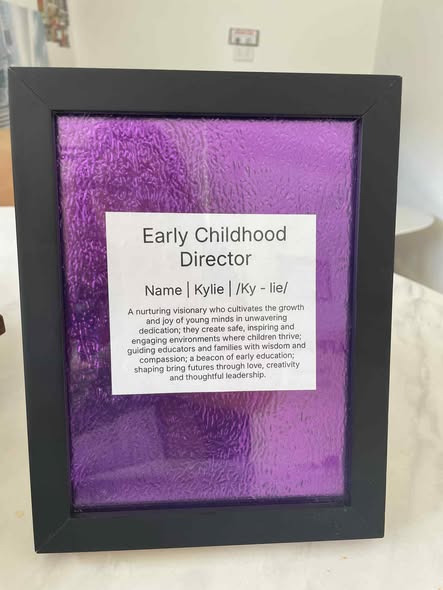 Tillys Cardiff Framed sign with "Early Childhood Director" text, featuring a description of nurturing leadership. Set on a purple textured background, conveying warmth and dedication.