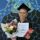 A young lady stands in front of a blue Aboriginal painted wall, wearing a black graduation gown and cap. She is holding a certificate, a kit-kat chocolate block and a colourful bunch of flowers. The image is bright and warm.
