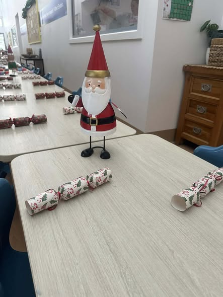 Festive classroom with a Santa decoration on a table lined with holiday crackers. Warm, cheerful atmosphere, ready for a celebration.