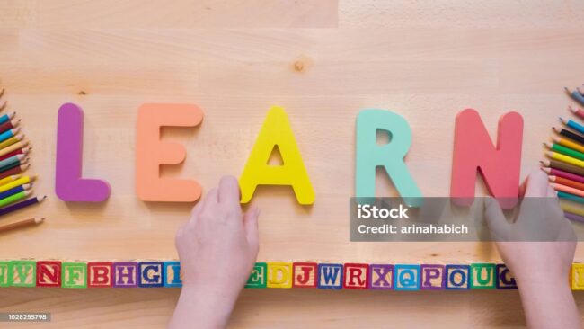 Word LEARN from multicolor wooden letters on wooden table.